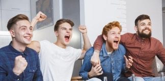 People in Wales spend 103 million more hours watching sport than breaking a sweat men watching sport tv together home screaming cheerful guys american football stag party team won hands up 108104841