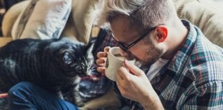 Look after your Wellbeing – Sharing Carmarthenshire’s Kindness #Sirgâredig young man drinking coffee on sofa 700 350