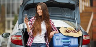 Revealed: Over a third of students regret taking their car to university young woman sitting in boot of car smiling and holding phone