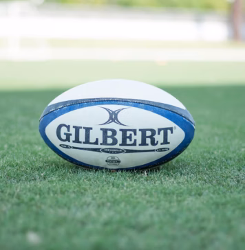 Wales squad named for Wheelchair Rugby League World Cup A photo of a Rugby ball with the text "GILBERT" on it underlined. It is in the middle of a rugby pitch.
